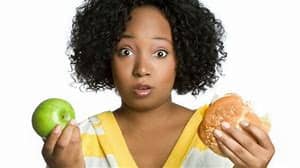  black woman holding an apple and burger. 