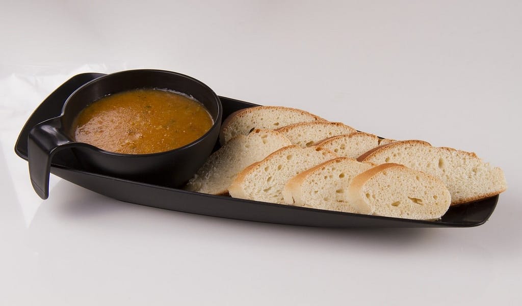  black tray with soup and slices of bread