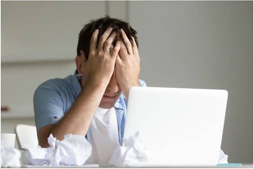 man at computer with his face in his hands suffering from depression because of osteoarthritis.